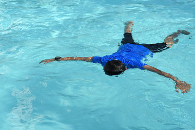 High angle view of boy floating in swimming pool