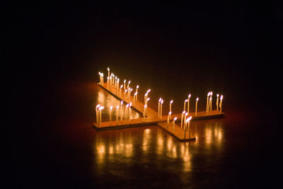 Illuminated bridge over river against sky at night