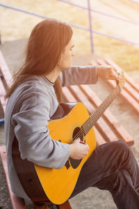 Side view of a young woman playing guitar