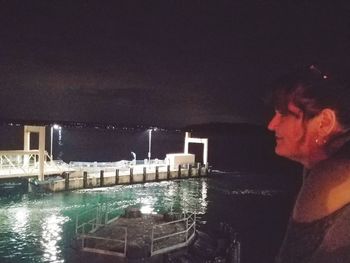 Side view portrait of young man standing in illuminated water at night