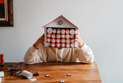 Girl holding model house sitting at home