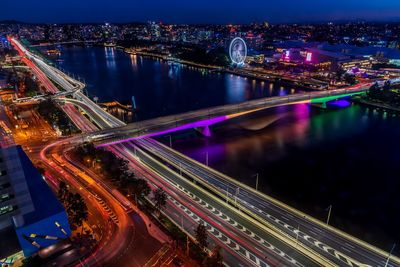 Aerial view of illuminated light trails on bridge in city at night