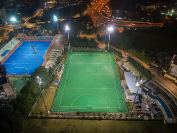 High angle view of illuminated soccer field in city at night