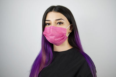 Portrait of beautiful woman wearing mask against white background