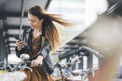 Young woman with bicycle using cell phone in the city