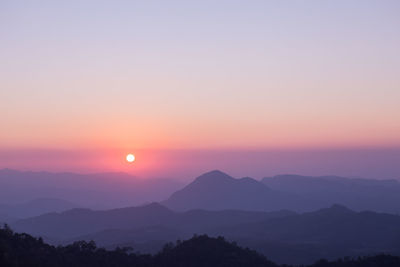 Scenic view of silhouette mountains against orange sky