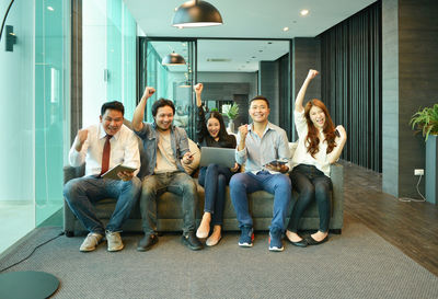 Happy colleagues sitting on sofa in office