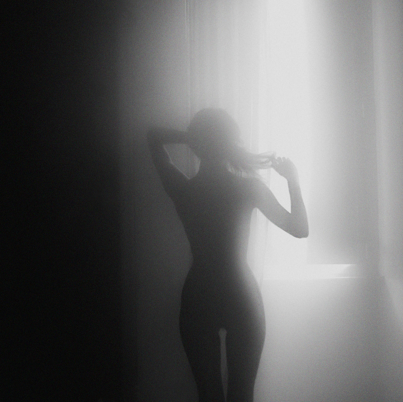 REAR VIEW OF SILHOUETTE WOMAN STANDING BY CURTAIN