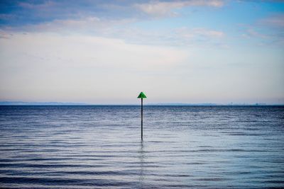 Pole in sea against sky