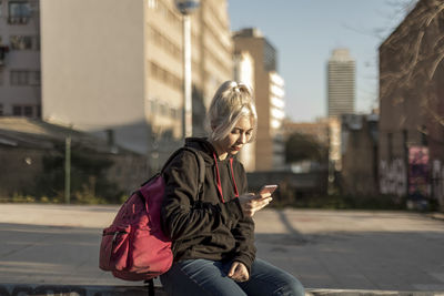 Portrait of young man sitting on street in city