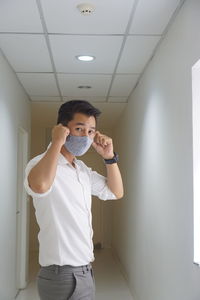 Portrait of young man standing against white wall