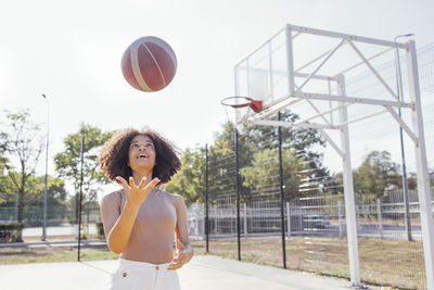 Portrait of young woman playing basketball at park