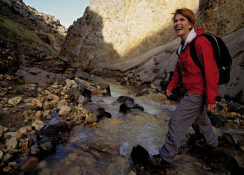 Mature woman crossing stream in landmannalaugar