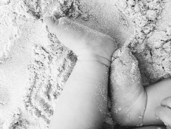 Low section of child on sand at beach