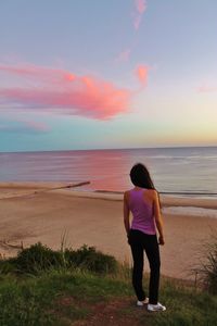 Rear view of woman standing on beach against sky