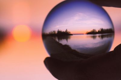 Close-up of hand against sky during sunset