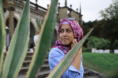 Portrait of young woman standing against blurred background