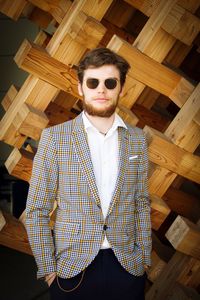 Portrait of young man standing against wood