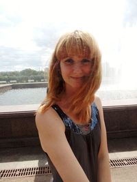 Portrait of smiling young woman against sky