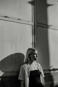 Woman looking away while standing against building