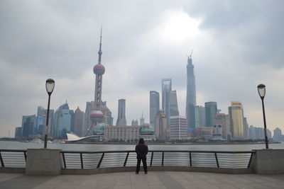 Rear view full length of man standing by huangpu river in city