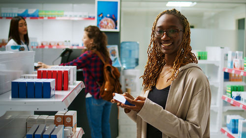 Portrait of smiling female friends using mobile phone while standing in store