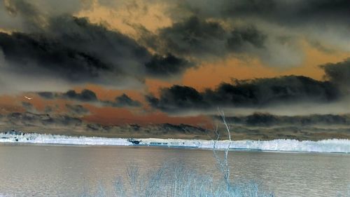 Scenic view of sea against cloudy sky at sunset