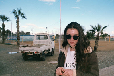 Woman in sunglasses on street against sky