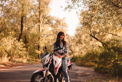 Woman riding bicycle on road against trees