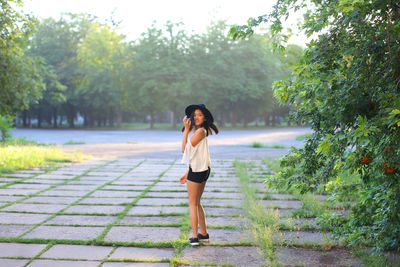 Full length of woman standing on footpath amidst plants