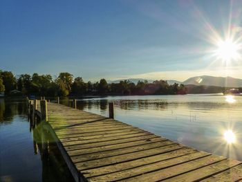 Pier over lake against sky during sunset