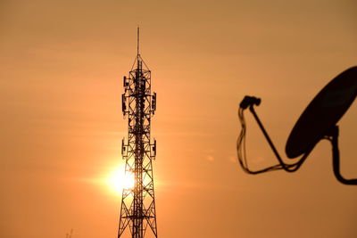 Silhouette of communications tower against sky during sunset