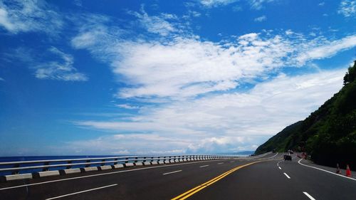 Road by sea against blue sky