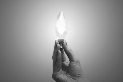 Close-up of hand holding illuminated light against white background