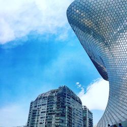 Low angle view of modern building against cloudy sky