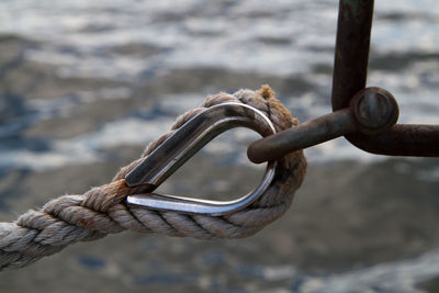 Close-up of rope tied to metallic loop against river
