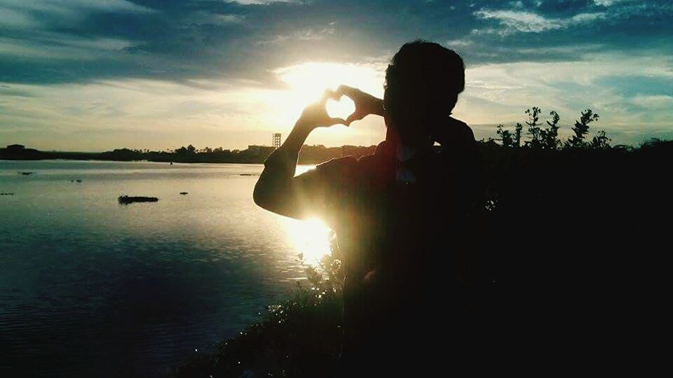 SILHOUETTE OF PEOPLE IN WATER AT SUNSET