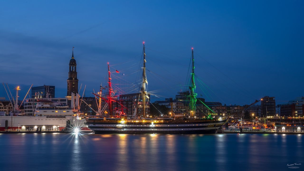 ILLUMINATED BUILDINGS IN CITY AT WATERFRONT