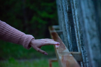 Close-up of hand touching fence against blurred background