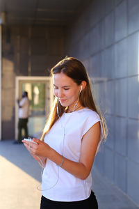 Young woman standing against wall