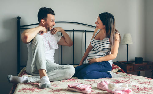 Young couple sitting on bed at home