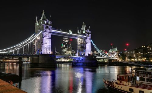 Illuminated bridge over river at night