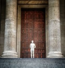 Statue of man standing in front of historical building