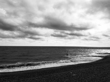 Scenic view of beach against cloudy sky