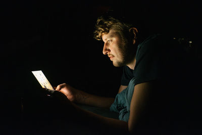 Side view of man using smart phone at night