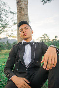 Portrait of young man standing against trees