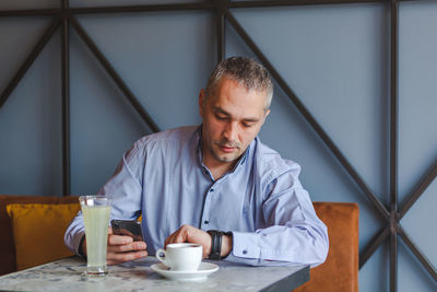 Businessman checking the time while sitting on table at restaurant