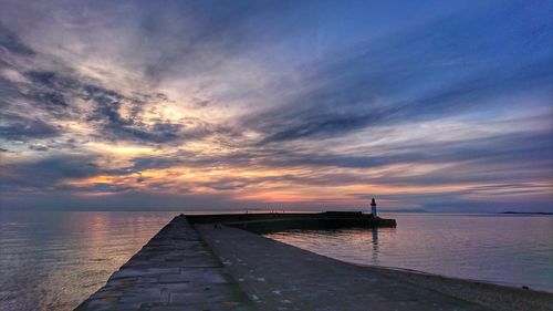 Pier over sea against sky during sunset