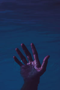 Cropped hand drowning in lake at night