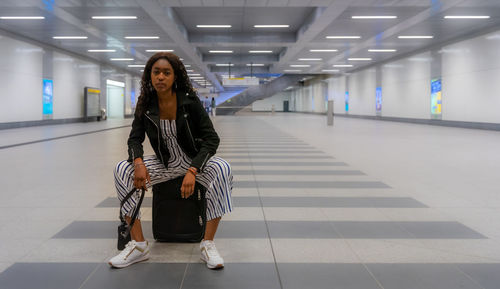 Portrait of woman with suitcase sitting at subway station